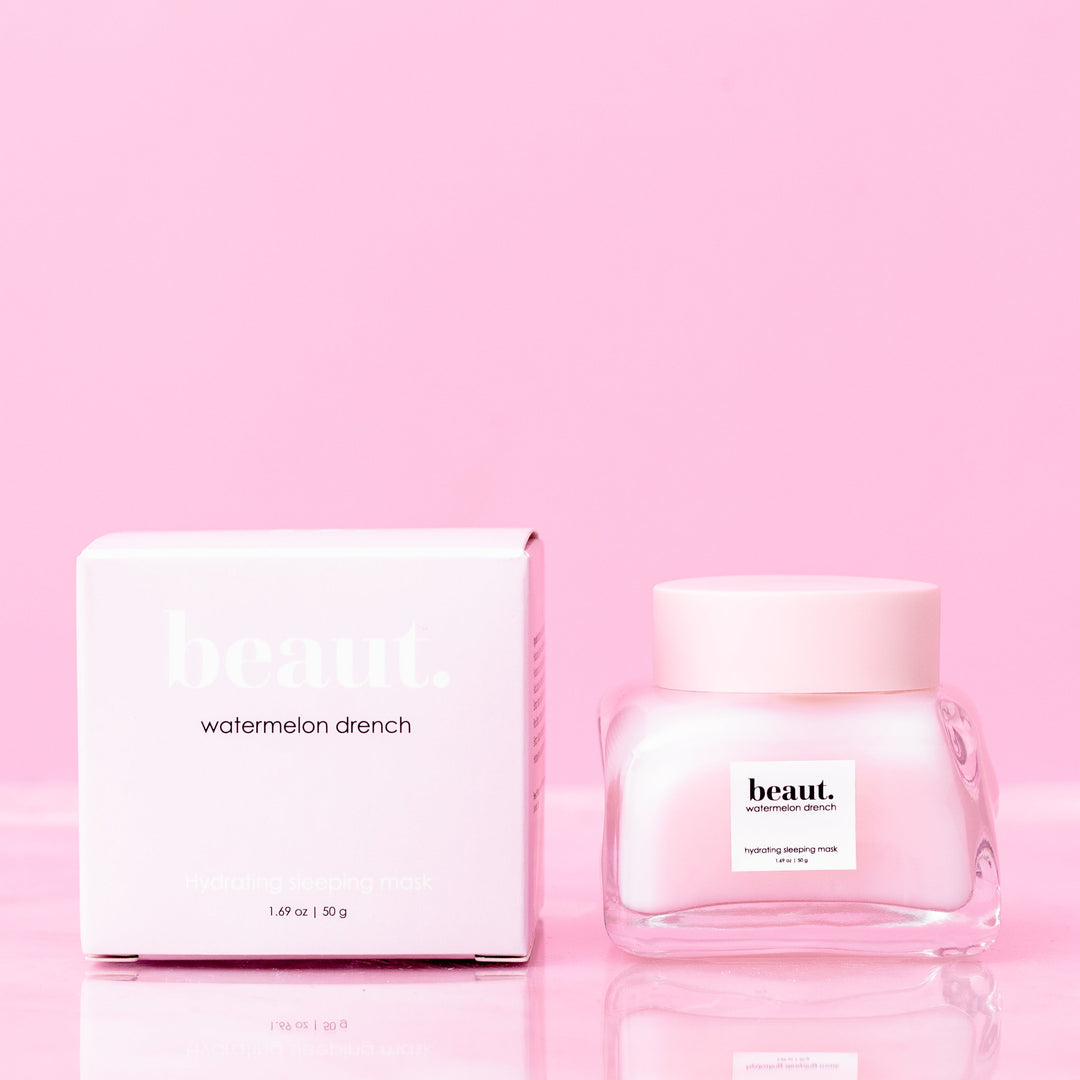 Beaut Watermelon Drench Hydrating Sleeping Mask 50g glass jar with pink lid next to pink retail box on pink reflective surface