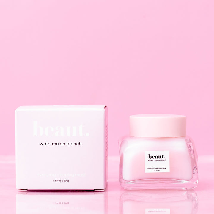 Beaut Watermelon Drench Hydrating Sleeping Mask 50g glass jar with pink lid next to pink retail box on pink reflective surface