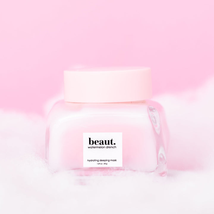 Beaut Watermelon Drench Hydrating Sleeping Mask 50g closed glass jar with pink lid nestled in white fluffy clouds against pink background